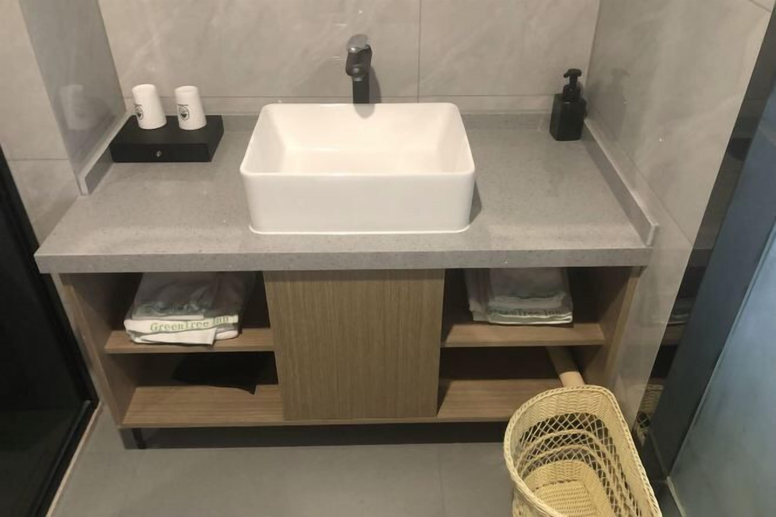 A bathroom with a white sink, two toilet paper rolls, a soap dispenser, and a wicker basket.