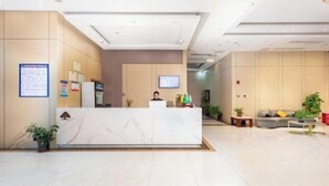 A modern hotel reception area with a marble counter, a digital screen, and a seating area with plants. - GreenTree Inn (Nantong Shanghe Plaza) (Nantong)