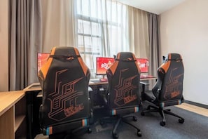 Et værelse med tre gamingstole, et skrivebord og to computerskærme.