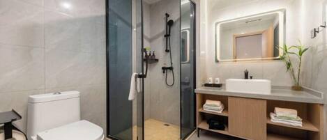A modern bathroom with a glass-enclosed shower, a white toilet, a vanity with a mirror, and a sink.