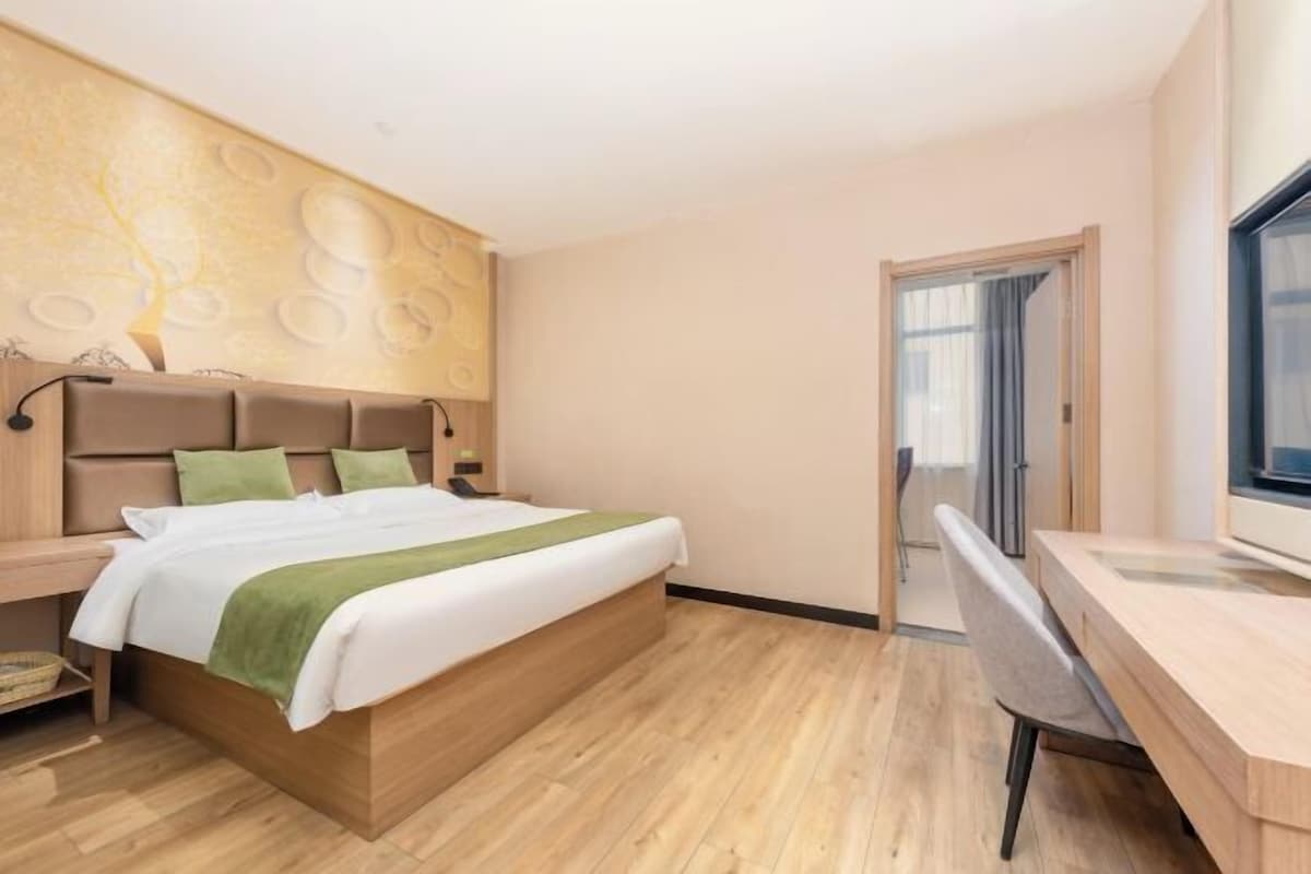 Et moderne hotelværelse med en træseng, et skrivebord og et stort vindue.