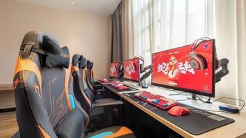 Un espace de jeu équipé de plusieurs écrans, de sièges de jeu et d’un bureau avec un clavier et une souris.