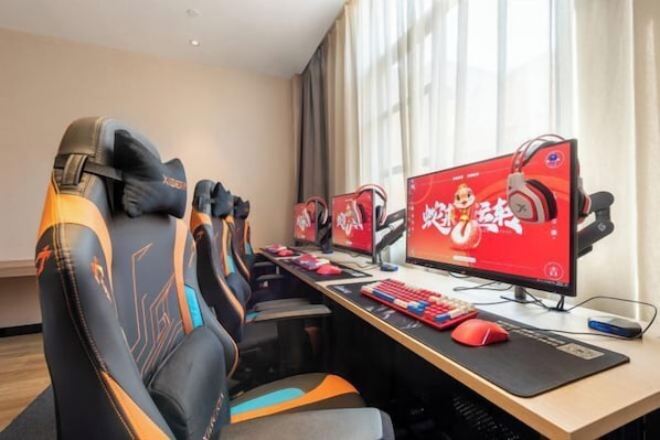 En gaming-opsætning med flere skærme, gaming-stole og et skrivebord med tastatur og mus.