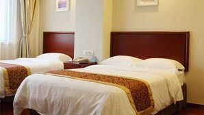 Une chambre d’hôtel avec deux lits, chacun doté d’une tête de lit en bois, d’une table de chevet et d’une lampe. Deux tableaux encadrés ornent les murs.