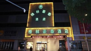 L’entrée d’un hôtel, avec une enseigne lumineuse affichant des caractères chinois, une adresse clairement visible et un écran numérique au-dessus de l’entrée.