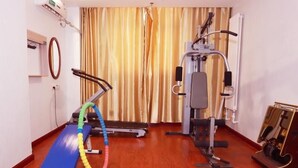 Une salle de sport à domicile équipée d’un tapis de sol bleu, d’un élastique de résistance multicolore, d’un vélo d’appartement et d’un appareil de musculation.