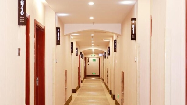 Un couloir d’hôtel avec des portes numérotées de 8710 à 8712, donnant sur un espace central où se trouve une sortie de secours.