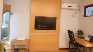 A hotel room with a wooden cabinet, a window, a desk with a chair, a potted plant, and an air conditioning unit. - Greentree Inn Xinyang Gushi County Liaocheng Avenue (Xinyang)