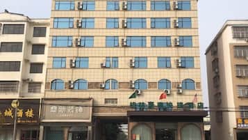 A hotel with multiple floors, a prominent entrance, and several cars parked in front.