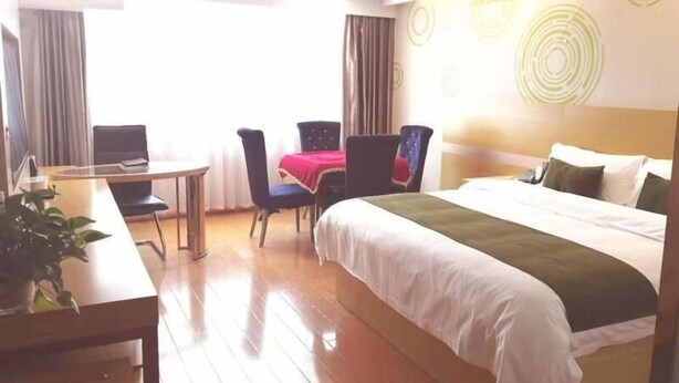 A hotel room with a bed, a desk with a laptop, two chairs, and a potted plant. - Greentree Inn Xinyang Gushi County Liaocheng Avenue (Xinyang)