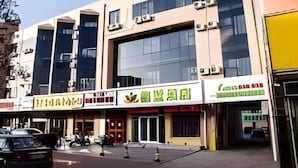 A building with multiple storefronts, including a restaurant with a green sign. - Greentree Alliance Texas Railway Station Municipal Hospital Hotel (Dezhou)