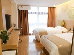 Hotelkamer met twee bedden, een bureau, een televisie, een airconditioner en een raam met gordijnen.
