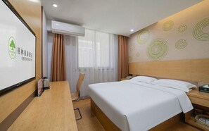 Een hotelkamer met een bed, een bureau, een stoel, een airconditioner, een raam met gordijnen en een wand met ronde patronen.
