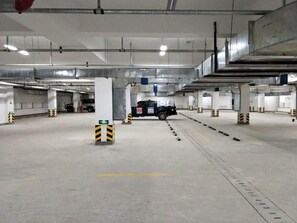 Un parking intérieur à plusieurs niveaux, avec des piliers en béton et un chemin dégagé menant aux véhicules.