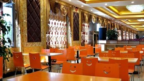 A restaurant with orange chairs and tables, a chandelier, and decorative wall panels. - Greentree Alliance Hotel (Tacheng)
