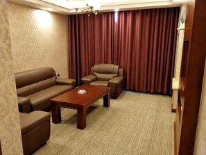 Une chambre d’hôtel avec un canapé, un fauteuil et une petite table.