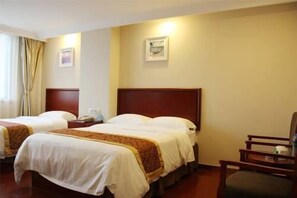 Habitación de hotel con dos camas, cabecero de madera, una silla e imagen en un marco en la pared.