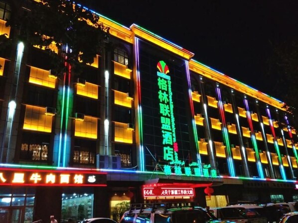 Un hotel con varios pisos, balcones y una fachada muy iluminada.