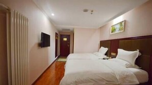 A hotel room with a wooden floor, a bed with white bedding, a flat-screen TV mounted on the wall, and a painting on the wall. - Greentree Alliance Hotel (Tacheng)