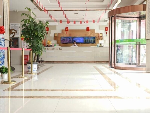 A reception area with a reception desk, a large potted plant, and a green sign.