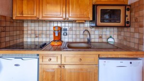 Une cuisine compacte dotée de meubles en bois, d’un four à micro-ondes, d’une machine à café et d’un lave-vaisselle.