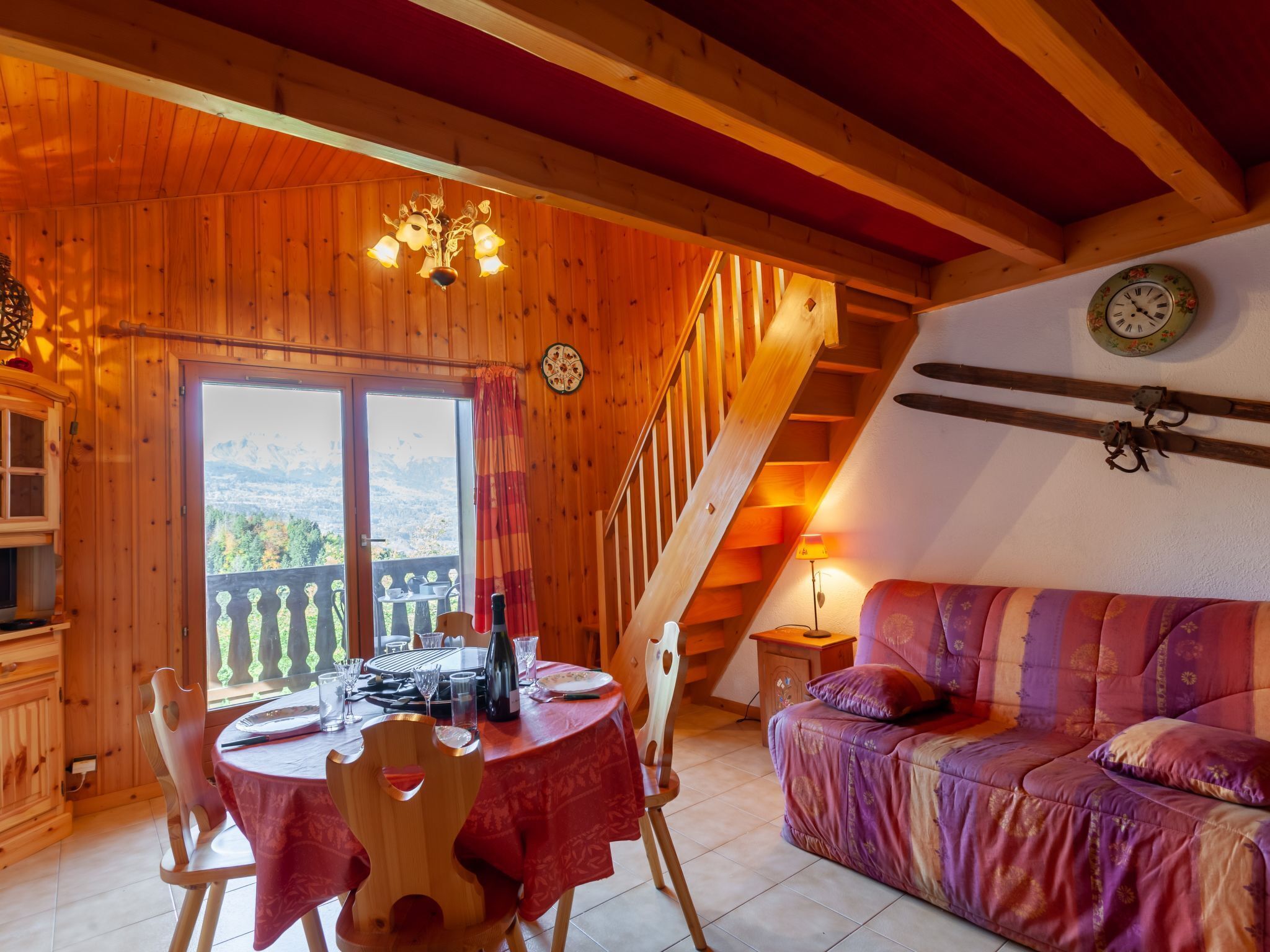 A cozy wooden interior with a dining area, a sofa, and a staircase.