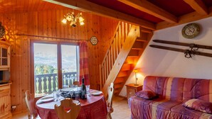 Un intérieur chaleureux en bois, avec un coin repas, un canapé et un escalier.