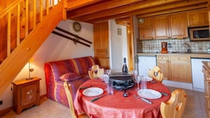 Une pièce confortable de style loft, comprenant un coin repas, un escalier en bois et une cuisine.