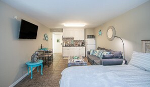 A compact living space with a kitchenette, a dining area, and a seating area with a sofa and a coffee table.
