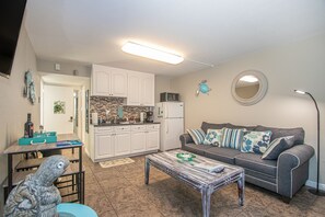 A compact living space with a kitchenette, a sofa, a coffee table, and a dining area.