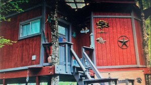 A red building with a staircase leading to a window, a flag, and a star emblem. - Summertime and the living is easy at the bearclaw  (Springville)