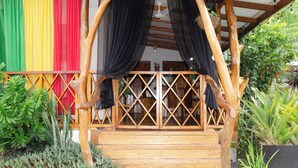 Une véranda en bois avec une balustrade en treillis, un auvent noir et un décor coloré.