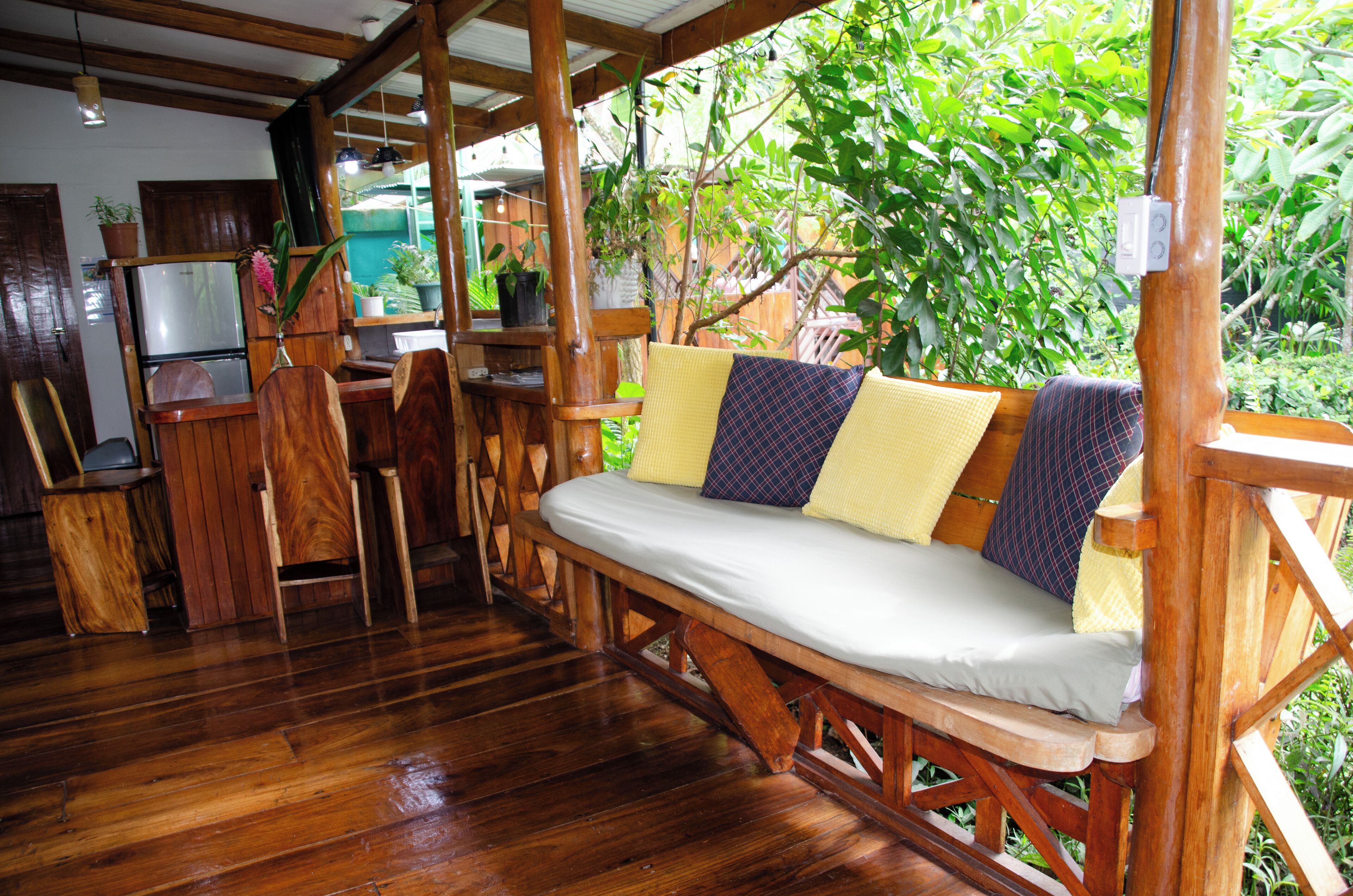 A wooden deck with a bench, a dining area, and a refrigerator.