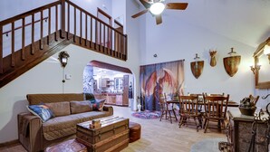 Ein geräumiges Wohnzimmer mit einer Holztreppe, einem Essbereich mit Holzkohlen und einem großen Gemälde an der Wand.