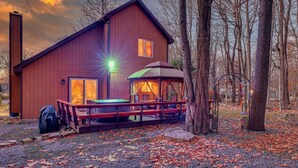 Eine rustikale Holzhütte mit einer Terrasse, einem überdachten Sitzbereich und einem sichtbaren Schornstein.
