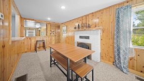 A wooden interior with a dining table and benches, a fireplace, and a window with a view. - River Front Home with Amazing views and a shared private island! (Newaygo)