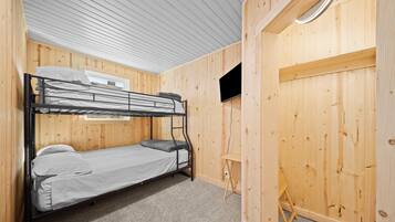 Une chambre avec un lit superposé, des murs en bois et un petit bureau.