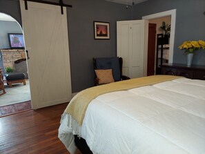 Une chambre à coucher avec un grand lit, une chaise, une armoire et un téléviseur.