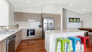 Cozinha moderna com armários de madeira, eletrodomésticos de aço inoxidável e uma ilha central com banquetas.
