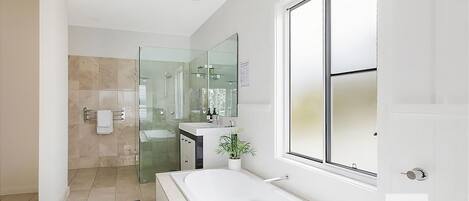Un bagno moderno con box doccia in vetro, uno specchio grande e un lavandino bianco.