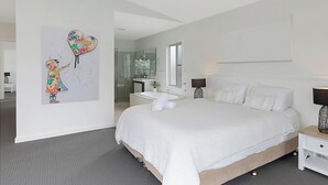A modern bedroom with a large bed, a bedside table, a nightstand, a mirror, and a wall art piece. - Sunset Central Coast - Lake, Kayaks & Jetty! (Mannering Park)