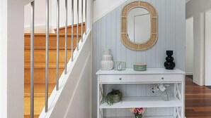 A staircase with wooden steps and white railings, a white console table with decorative items, and a mirror with a wooden frame. - Sunset Central Coast - Lake, Kayaks & Jetty! (Mannering Park)