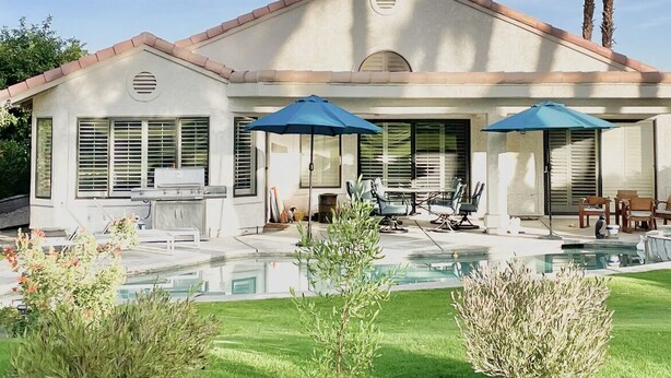 A house with a swimming pool, patio furniture, and palm trees. - Spacious home in Avondale Golf Club. Available May 1st 2025! (Palm Desert)
