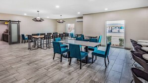 A spacious dining area with a large table and blue chairs, a sliding door leading outside, and a view of a gas station through the door.