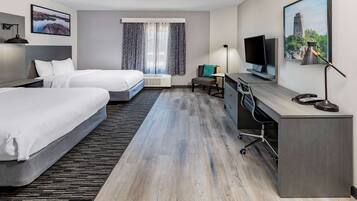 Une chambre d’hôtel avec deux lits, un bureau, une télévision et une fenêtre avec des rideaux.