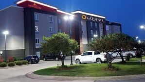 A multi-story hotel with a 'Hawthorn' and 'La Quinta' sign, parking area, and a well-maintained lawn.