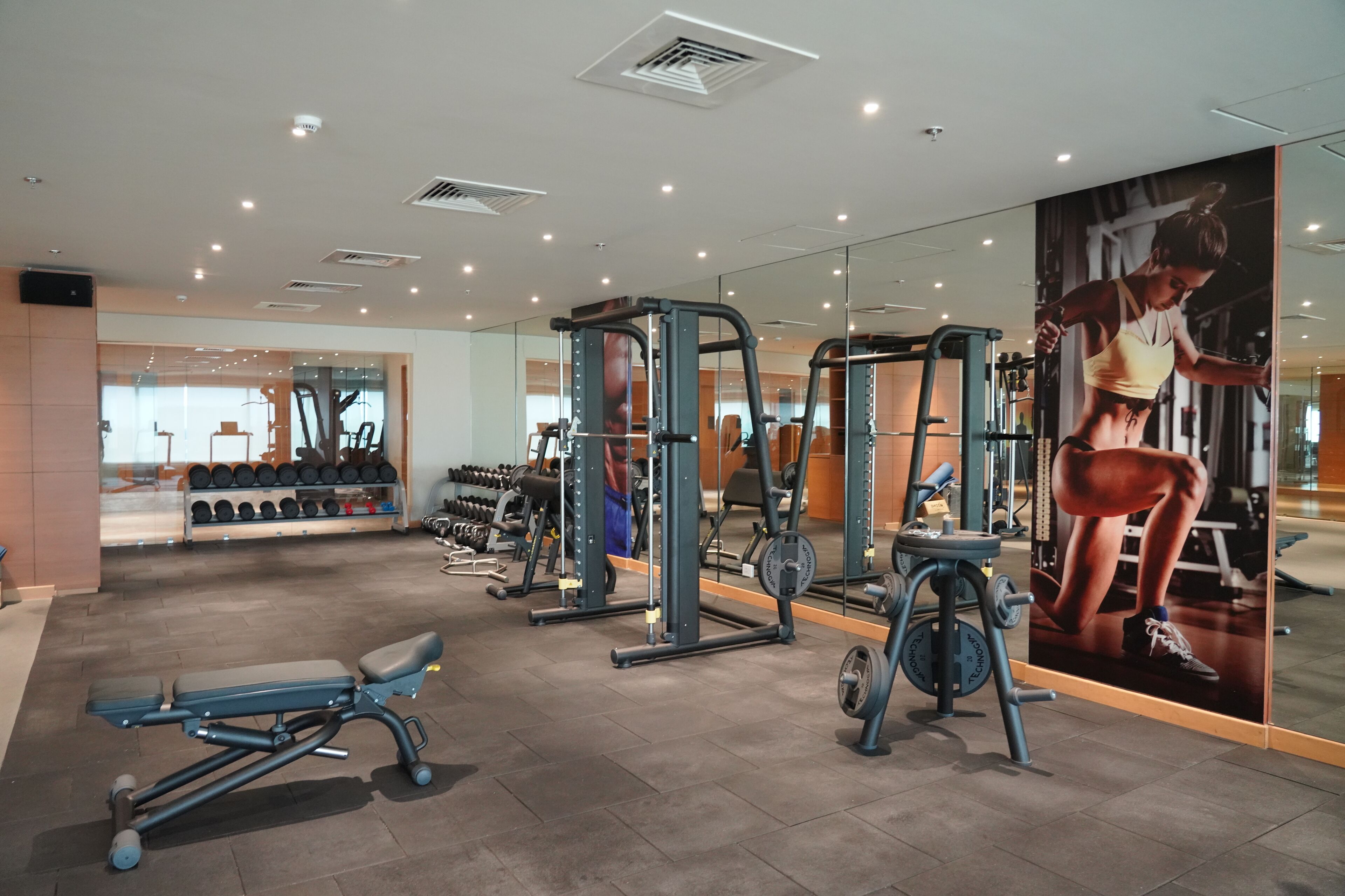 A gym with various exercise equipment, including a bench, a squat rack, and dumbbells.