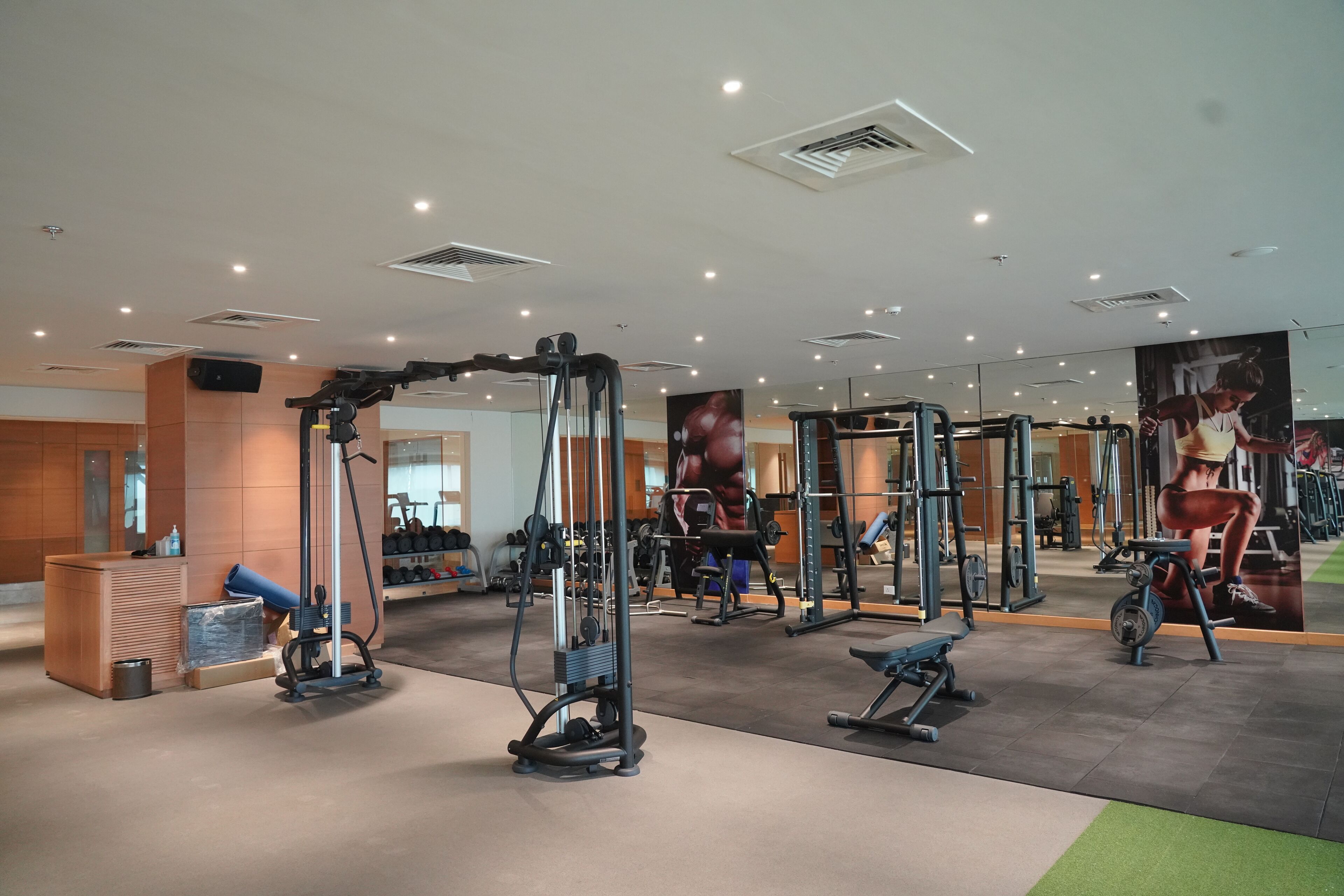 A modern gym with various exercise equipment, mirrors, and a reception area.