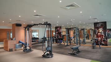 A modern gym with various exercise equipment, mirrors, and a reception area.