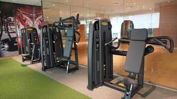 Una palestra con diverse macchine per esercizi, un tappeto verde e uno specchio grande.